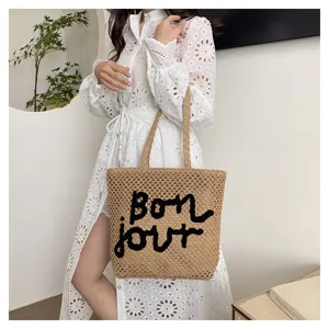 Fashionable straw woven shoulder bag with chic black letter embroidery for women summer beach.