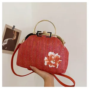 Détail du sac de soirée en paille tissée, broderie florale, poignée en métal et fermoir rétro.