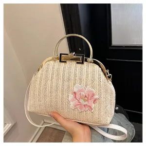 Vue détaillée d'un sac de soirée en paille tissée vintage avec broderie florale rose et cadre en métal.