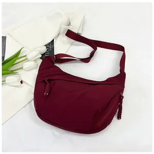 Vue détaillée du sac bandoulière croissant rouge vin avec une large sangle et des poches zippées.