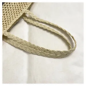 Close up of the woven straw shoulder bag handle, detailed view showcasing fine braided craftsmanship.