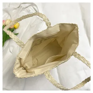 Beige straw tote bag with braided handles, spacious interior with zipper pocket for beach vacation.