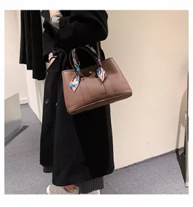 Gros plan sur le cabas en cuir marron avec foulard en soie, texture et détails de poignée.