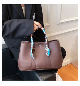 Détail du sac cabas en cuir marron avec foulard coloré, élégant sac à main pour le travail.