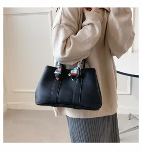 Vue rapprochée d'un sac cabas en cuir noir avec foulard coloré sur la poignée.
