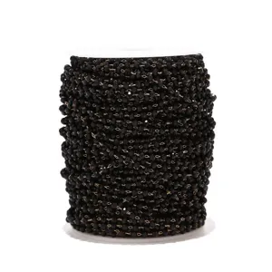 Close-up detail view of black crystal bead chain on a spool for DIY jewelry crafts.