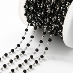 Gros plan détaillé sur une chaîne de perles noires enroulée pour création de bijoux.