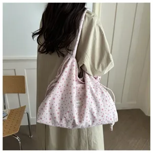 Vista detallada de un bolso shopper de pana con estrellas rosas llevado al hombro, estilo acogedor.