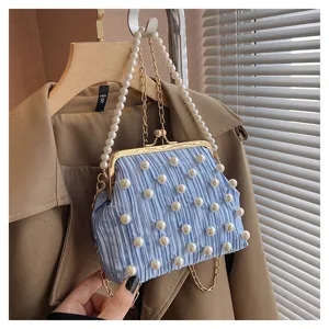 Détail rapproché du sac à main plissé bleu clair avec fermoir baiser, perles et chaîne chic.