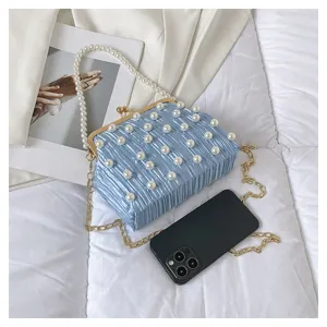 Détails en gros plan du sac à main de soirée plissé bleu avec poignée perle et chaîne.
