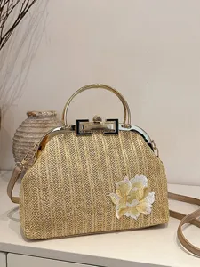 Sac à main rétro en paille tissée avec poignée en métal et détail de fleurs brodées.