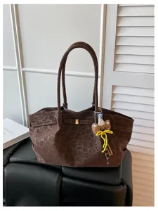 Vista dettagliata della borsa a tracolla vintage maculata con ciondolo a forma di orsetto.