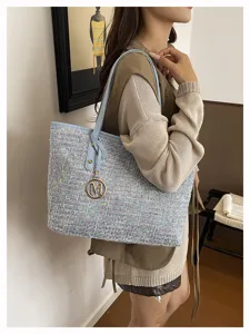 Detailed shot of stylish tweed shoulder bag with multi-color speckles and metal M charm.