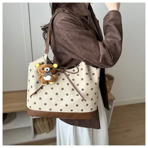 Vista dettagliata di una borsa tote a pois elegante con simpatico ciondolo orsetto di peluche.