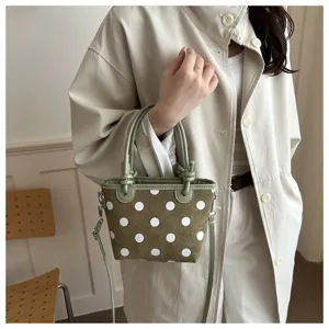 Vista dettagliata della borsa a pois verdi con elegante manico in pelle e pratica tracolla.