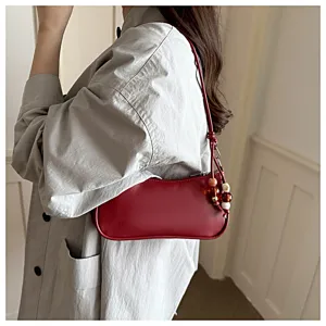 Red PU shoulder bag detail, stylish underarm handbag with beaded charm strap for women.
