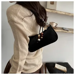 Minimalist PU leather shoulder bag for women, stylish black baguette purse with beaded charm.