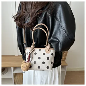 Vista dettagliata della borsa a secchiello a pois con grazioso ciondolo orsetto di peluche e finiture.