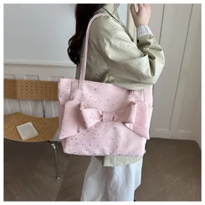 Dettaglio borsa shopper rosa con grande fiocco decorativo e stampa con stelle argentate.