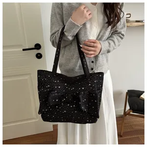 Vista dettagliata di una elegante borsa tote nera con stelle bianche e grande fiocco.