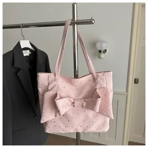 Vista dettagliata della borsa rosa con motivo a stelle, grande fiocco e spallacci.
