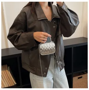Detailed view of a mini metallic silver pleated handbag with a chain strap and metal handle.