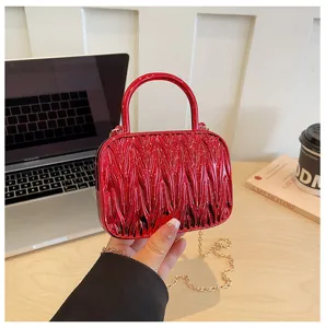 Red shiny ruched mini handbag detail showing unique texture, round handle and gold chain.