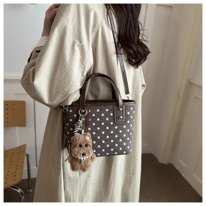 Braune gepunktete Eimer Tasche Detailansicht mit niedlichem flauschigen Welpen Anhänger.
