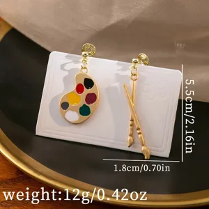Asymmetrical paint palette and brushes earrings detail shot, art style cute drop earrings.