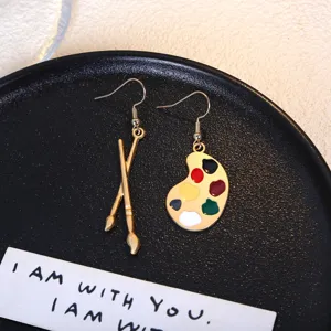 Asymmetric paintbrush and palette earrings, fun retro art style design metal alloy studs.