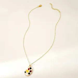 Gold-plated artistic paint palette pendant necklace detail view, vintage literary style jewelry.