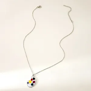 Detailed view of a creative mini paint palette pendant necklace, silver chain jewelry for art lovers.
