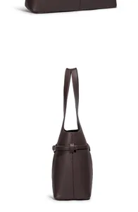 Zijdelingse detailweergave van de elegante donkerbruine zachte lederen emmertas en tas.