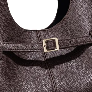 Detail van bruinenerflederen tas met een gouden metalen gesp en fijne stikseltextuur.