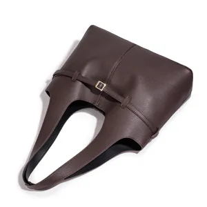 Detailopname van donkerbruine zachte lederen schoudertas met stijlvolle riem en metalen gesp.