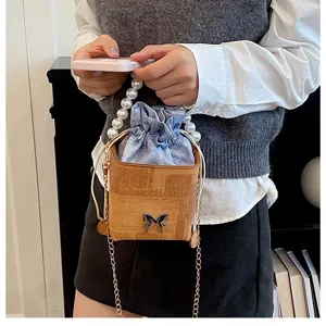 Chic bucket bag with pearl handle and denim inner pouch, stylish accessory for daily wear.
