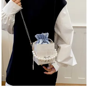 Close-up of the stylish pearl handle and blue drawstring detail on the chic mini bucket bag.