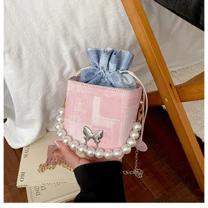 Detailed view of women bucket bag with pearl handle, denim drawstring and cute butterfly decor.