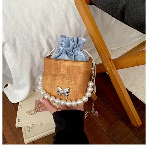 Stylish drawstring bucket bag featuring pearl handle and chic denim pouch for women daily use.