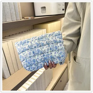 Blauw-witte gewatteerde clutch met bloemprint, elegante cosmetische tas in minimalistische stijl.