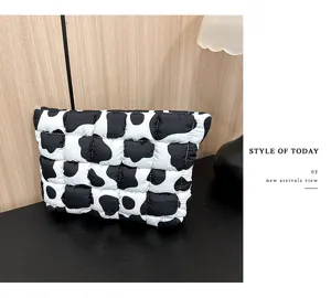 Gedetailleerd overzicht van trendy zwart-witte koeienprint puffer cosmetische tas.