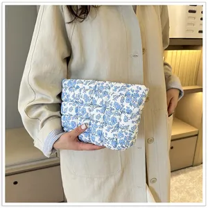 Chique blauwe bloemende gewatteerde clutch detailshot, stijlvolle gewatteerde cosmetictas dames.