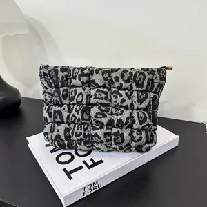 Detailopname van het gewatteerde toilettasje met luipaardprint en zachte textuur.