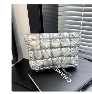 Zilveren metallic gewatteerde puffer clutch tas detail, zachte cosmetische etui.
