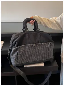 Detailansicht der multifunktionalen Reisetasche mit Karomuster-Tasche und stabilen Griffen.