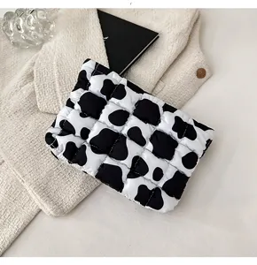 Gedetailleerde opname van een chique zwart-witte gewatteerde koeienprint make-up etui.