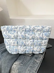 Wit-blauwe gebloemde gewatteerde make-tas, stijlvolle gevoerde handtas voor dames.