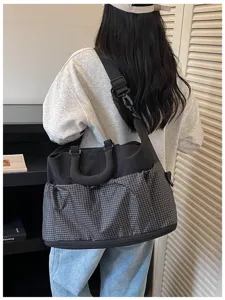 Detailansicht der multifunktionalen Reisetasche mit schwarzem Karomuster und Schultergurt.