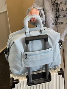 Hellblaue Reisetasche mit Kofferhaltegurt, ideal für Wochenendtrips und Fitnessaktivitäten.