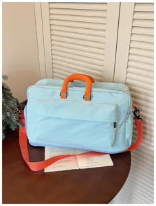 Sac de voyage bleu clair avec poignées orange vives et grande poche frontale zippée.